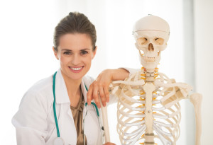 Portrait of smiling medical doctor woman near human skeleton anatomical model