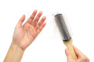 Hair loss in woman hands and brush, on white background