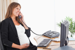 Attractive pregnant woman on the phone while working at the office